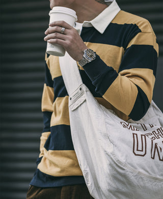 Yellow and navy striped rugby shirt worn with a white strap bag, front view