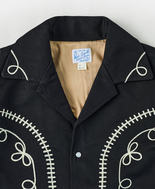 Black musician jacket close-up: notched collar with embroidered trim at shoulder seams