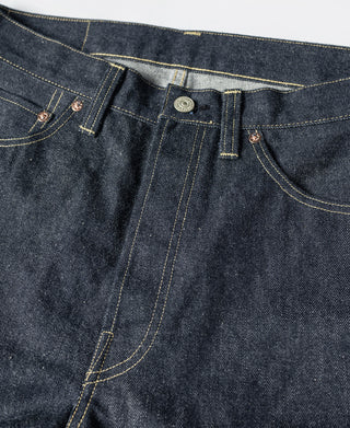 Indigo denim jeans close-up of waistband, coin pocket, and contrast yellow stitching.