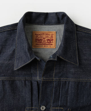 Indigo denim jacket collar with interior brand patch and button placket