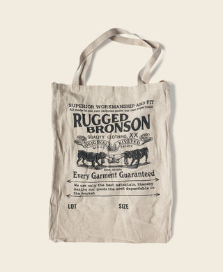 Natural linen tote bag with printed RUGGED BRONSON logo and handle loop.