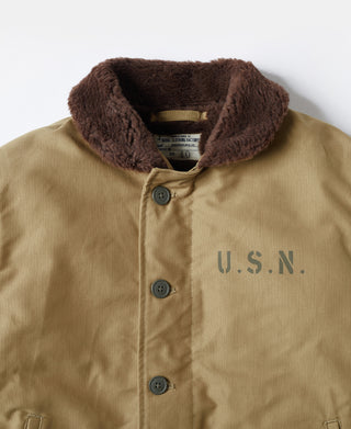 Khaki deck jacket close-up: brown sherpa collar, snap placket, U.S.N. emblem