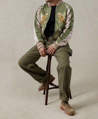 Reversible souvenir jacket worn open: green front with bird embroidery and white striped cuffs