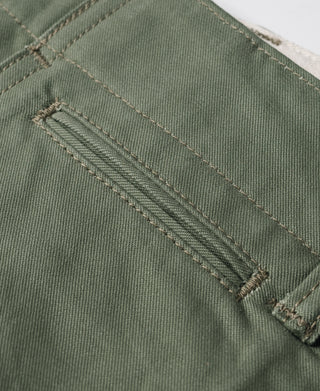 Olive trouser fabric close-up with stitched seam and textured weave