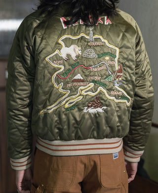 Olive reversible souvenir jacket worn with Alaska map patch graphic and ribbed striped hem.