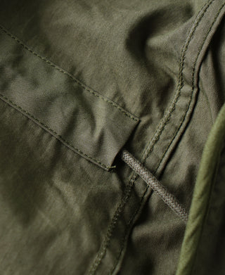Olive M-65 parka pocket seam with reinforced stitching and tab corner.