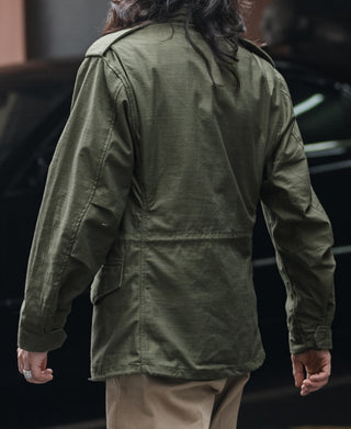 Olive field jacket back view with button pockets and curved hem