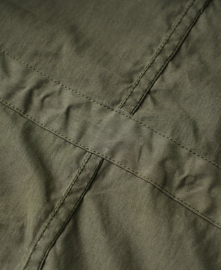 Olive M-65 parka front panel with diagonal stitched seam and hem reinforcement.