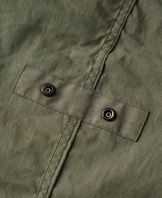 Olive M-65 parka front cuff tab with two dark snap buttons on flap.