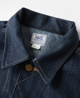 Indigo denim jacket collar and front button placket with brand patch label.
