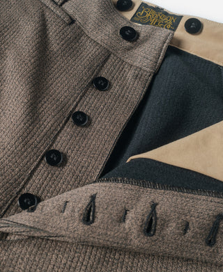 Brown stripe pants close-up of front buttons, waistband label, and pocket stitching