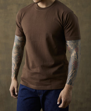 Coffee-brown crewneck cotton T-shirt on model with short sleeves and arm tattoos