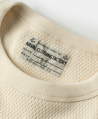 Thermal waffle-knit shirt neckline label detail on light apricot/cream fabric