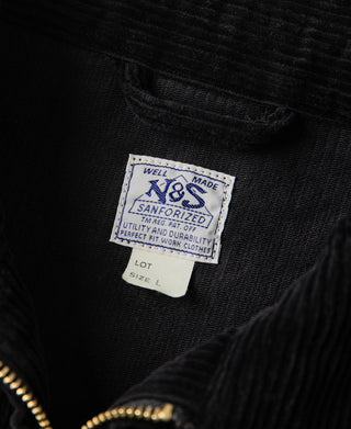 Black corduroy jacket label at chest, with gold zipper trim and textured fabric