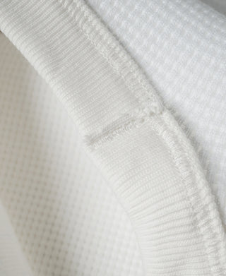 White waffle-knit cotton fabric close-up with visible stitch lines