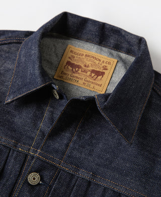 Indigo denim jacket collar with tan brand label on inner neckline