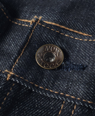 Dark indigo denim jeans button with embossed logo and tan contrast stitching