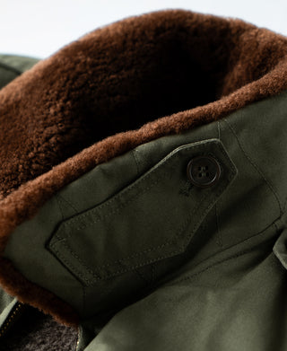 Olive flight jacket chest pocket with brown shearling edge and button tab
