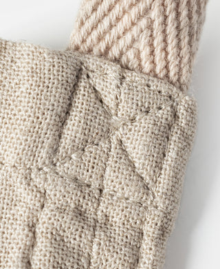 Natural linen tote bag fabric with stitched patch detail at a corner.