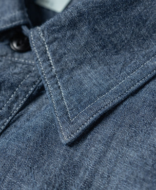 Blue chambray shirt placket and pointed collar with stitched seams and black buttons.