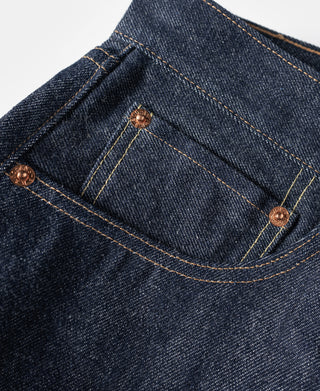 Dark blue denim jeans front pocket with curved coin pocket seam and copper-toned buttons