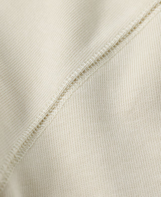 Close-up of light cream henley fabric seam and knit texture