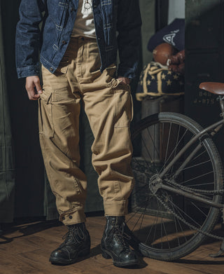 Khaki relaxed fit field pants on a model standing, cargo pockets visible.