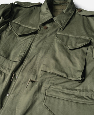 Olive field jacket with flap pockets, drawstring detail, and snap cuffs
