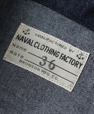 Indigo denim label patch on utility jacket with “NAVAL CLOTHING FACTORY” text