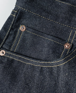 Indigo denim jeans close-up of coin pocket with copper-tone rivets and stitching.