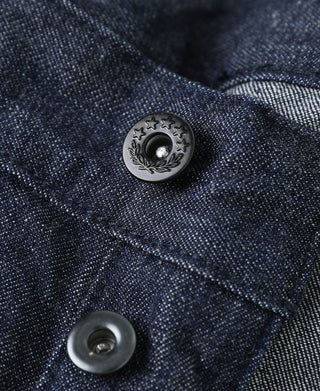 Indigo denim detail showing decorative coin pocket button and fabric weave