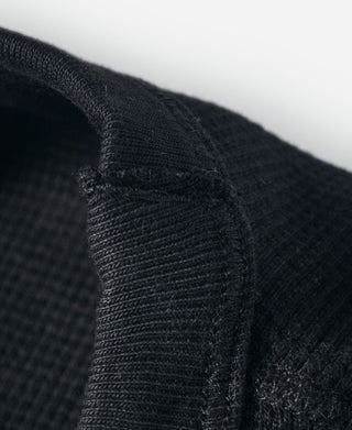 Black waffle-knit shoulder seam and textured fabric close-up