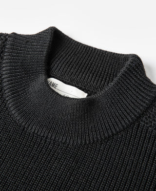 Black wool crewneck sweater close-up, ribbed collar and interior tag