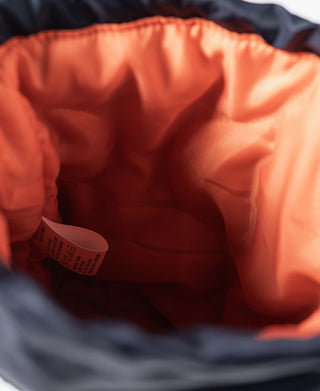 Orange interior lining inside navy chalk bag with attached paper label