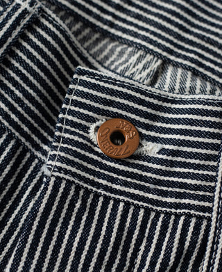 Striped carpenter pants fabric with brown button on pocket flap and contrast stitching.