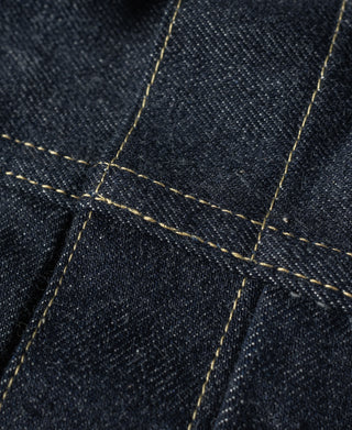 Close-up of indigo denim jacket seams with yellow contrast stitching.