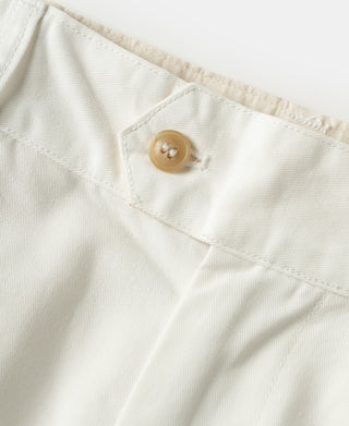 White trouser waistband detail with tan button and stitched front panel.
