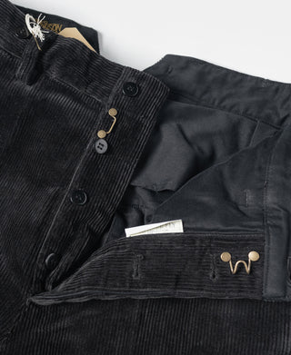 Black corduroy pants with button closure and decorative brass-and-gold hardware.