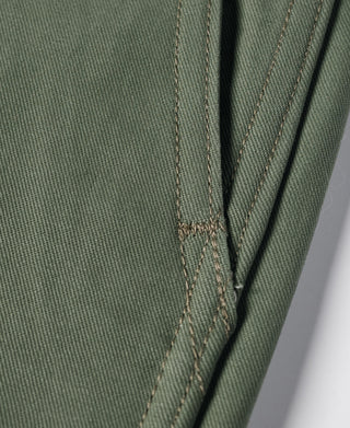 Olive trouser pocket seam close-up with stitching details along the side opening
