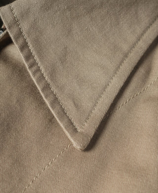 Khaki jacket fabric close-up with stitched V-shaped collar seam detail