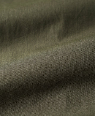 Olive parka fabric close-up with textured weave and stitching.