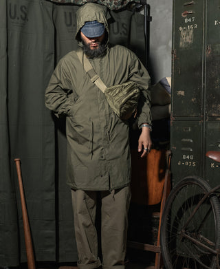 Olive M-65 parka front view with hood, stand collar, and drawstring waist.