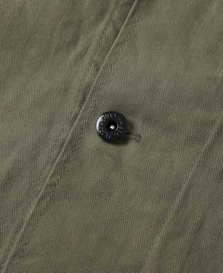 Olive jacket close-up of dark button on herringbone weave fabric