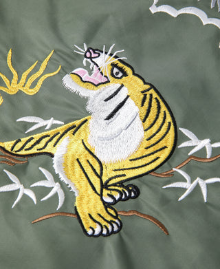 Close-up embroidery of a yellow tiger face with white mane on olive tote fabric