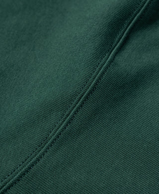 Green T-shirt side seam detail with stitched construction along the hem.