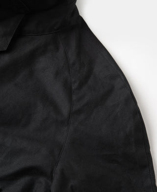 Black waxed jacket fabric close-up with seam details and angled pocket stitching