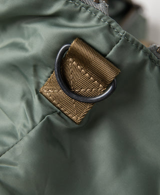 Sage green fabric with brown webbing loop and stitched corner reinforcement