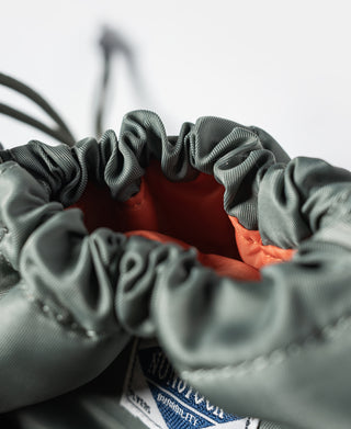 Olive chalk bag opening with ruched drawstring and visible orange inner lining