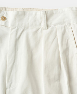 White cotton twill trousers showing front pleats and belt-loop waistband.