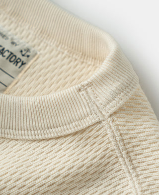 Thermal waffle-knit shirt front placket seam and ribbed collar on light apricot/cream